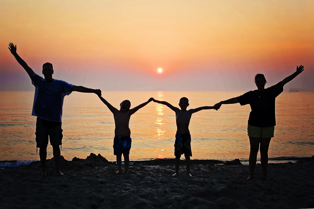 image: family holding hands on beach at sunset