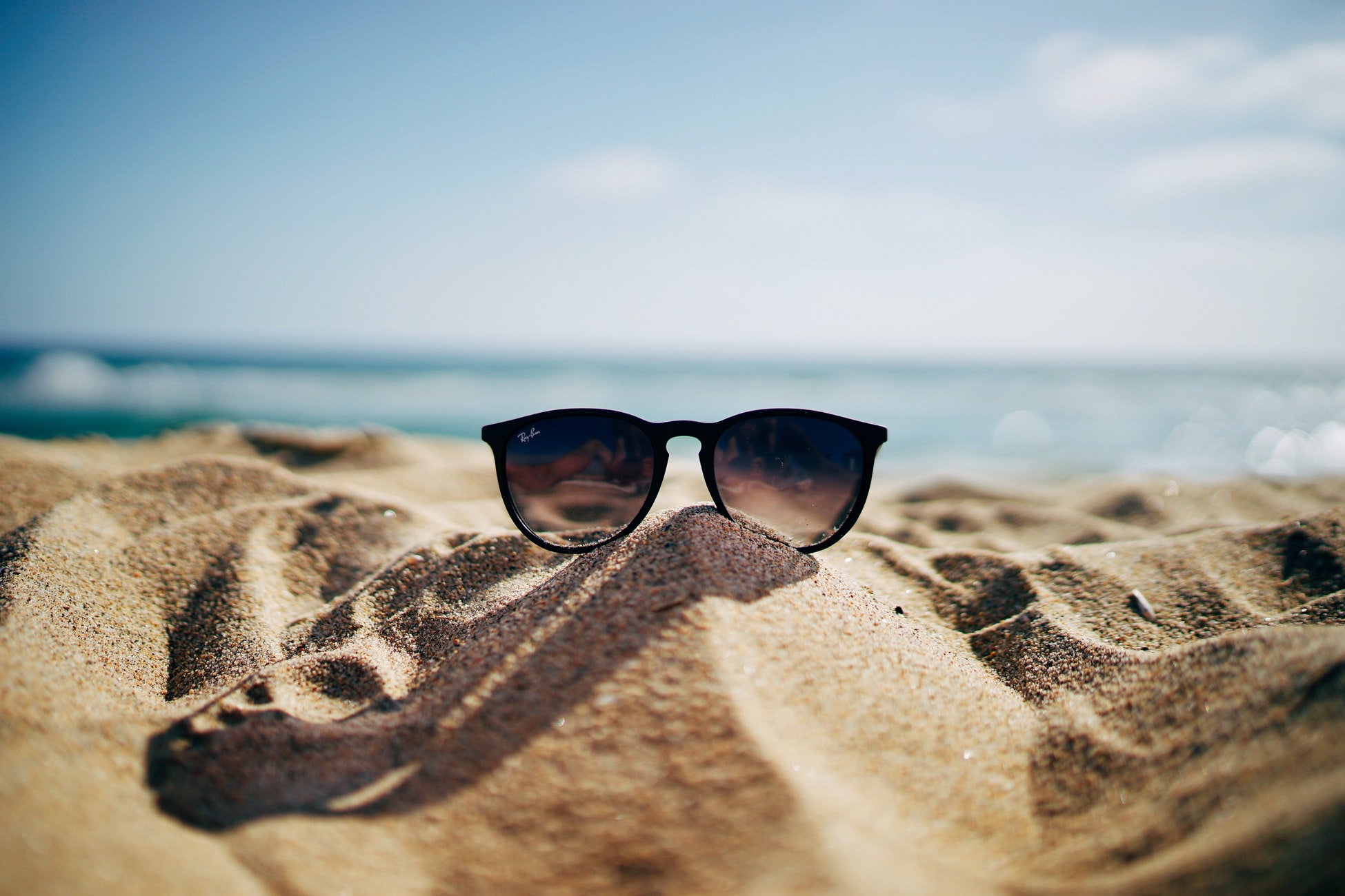 image: sunglasses sitting on sand at beach